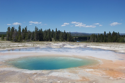 Crested Pool Hot Spring at Upper Geyser Basin in Yellowstone National Park in Summer. Bubbling, Boiling and Smoking Sulphor Geyser under summer skyscape. Although it is considered a spring, Crested Pool sometimes erupts like a Geyser. Crested Pool Spring, Upper Geyser Basin, Yellowstone National Park, Wyoming, USA, North America