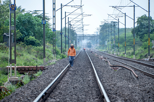 Pune, India - September 10 2023: Railway employee wearing orange jackets walking on railways at Pune India.