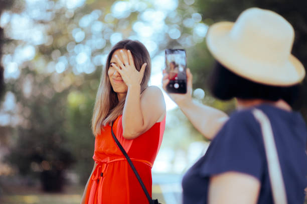 woman hiding her face from someone filming her in public - shy women camera paparazzi photographer imagens e fotografias de stock