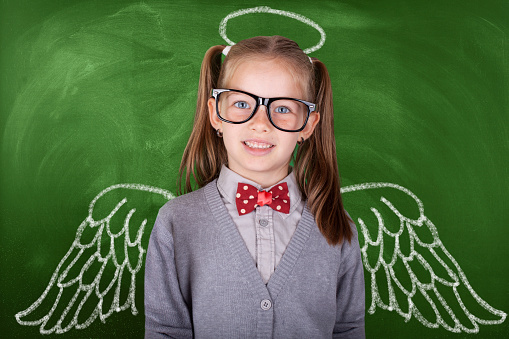 Schoolgirl against chalkboard, with drawn angel wings