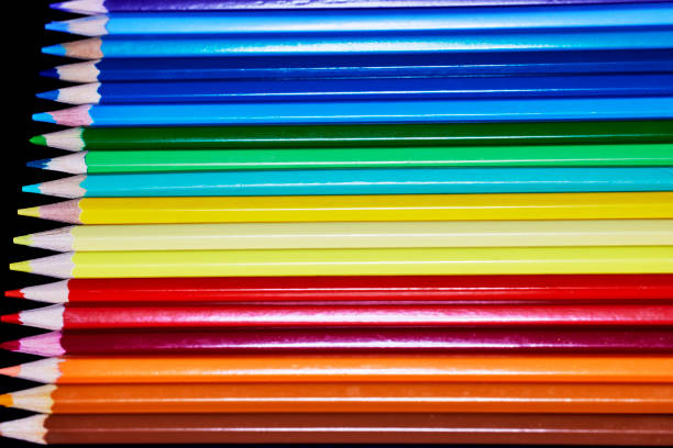 Close up of a row of colored pencils isolated on black