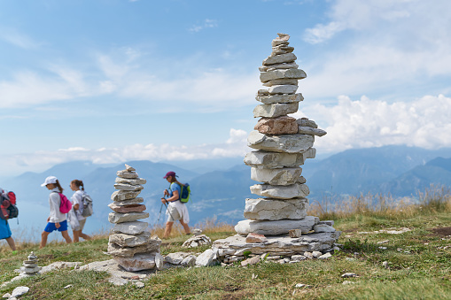 Malcesine, Italy – July 30, 2023: stones piled up by tourists and some hikers on the mountain top of Monte Baldo at Lake Garda near Malcesine in Italy