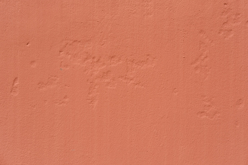 Part of a textured peach colored concrete wall.