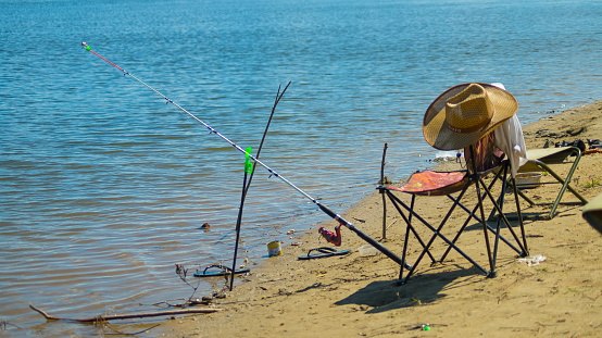 A fisherman's chair and fishing rod on the shore of the lake.