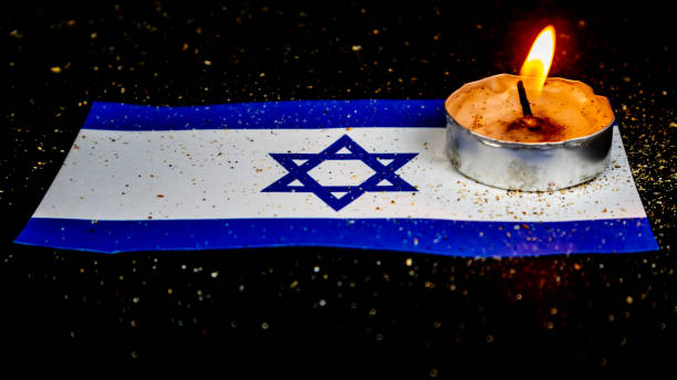 istock Israeli flag and candles burning above it, Holocaust memory day 1677374009