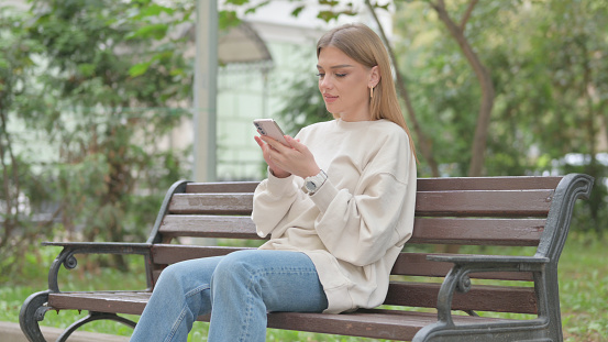 Casual Young Woman using Phone while Sitting Outdoor