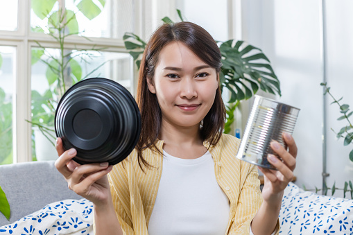 Asian women are showing plastic bowls and cans. Introduce the separation each type waste. Garbage sorting for recycle. Reduction of global warming. concept of environmental protection.