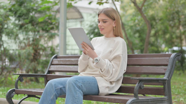 istock Casual Young Woman using Tablet while Sitting Outdoor on a Bench 1677481725