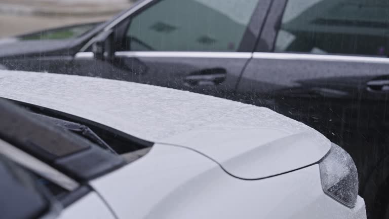 SLO MO: Heavy rain falling onto two cars parking in front of a residential building with reflection of white building on the car's window which the black car blocking the white car on a stormy day.