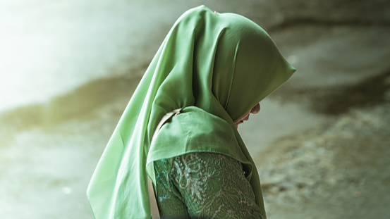 Ambon, Indonesia - August 31, 2023 : photo of a woman wearing a green hijab's waist up exposed to light