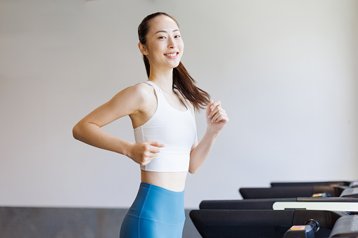 Young Asian woman running on treadmill