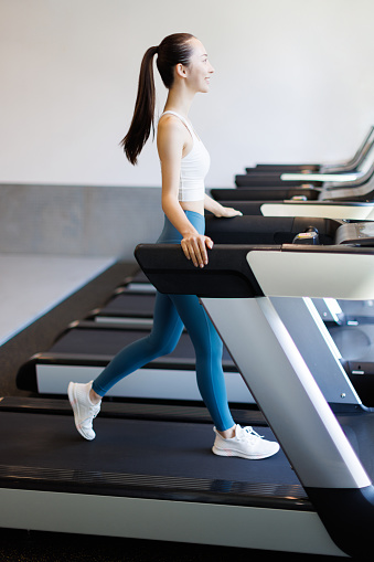 Young Asian woman walking on treadmill
