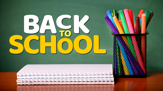 Welcome back to school background - Black blackboard, textbooks and apple on teacher's desk