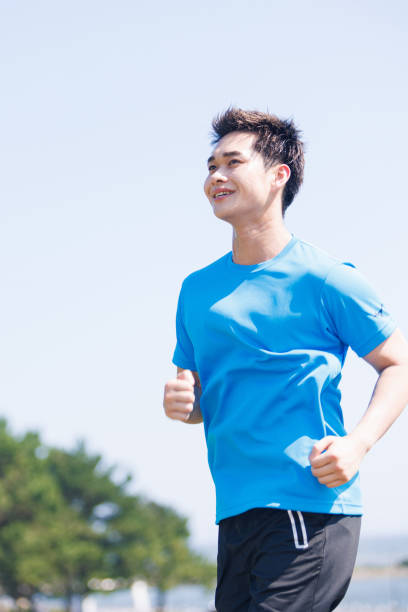 istock Young Asian man jogging at seaside 1677539739