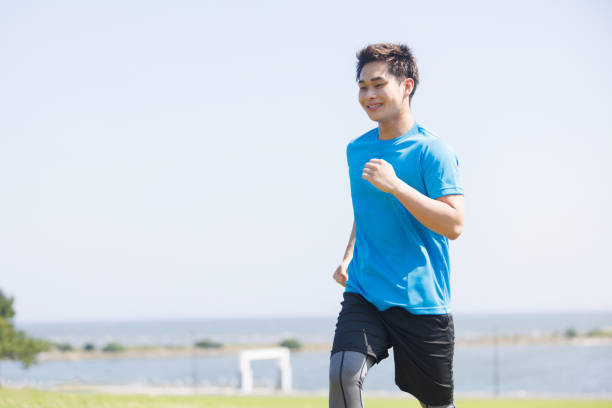 Young Asian man jogging at seaside