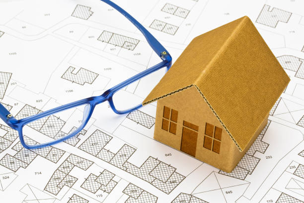 istock Imaginary cadastral map of territory with buildings and land parcel - concept with a small cardboard house 1677540447