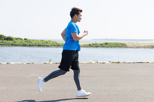 Young Asian man jogging at the seaside