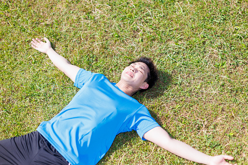 Young Asian man lying on the ground in the park