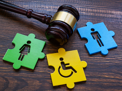 Gavel with puzzle pieces. Disabled person sign as a symbol of inclusion.
