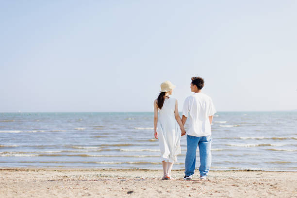 istock Young Asian couple standing at the beach 1677543835