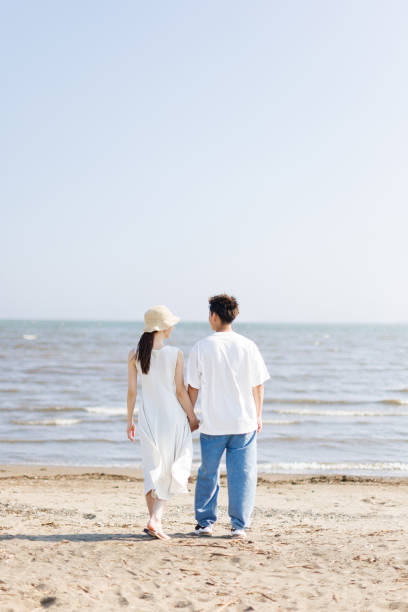 istock Young Asian couple standing at the beach 1677544343
