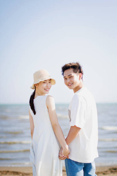 istock Young Asian couple holding hands at the beach 1677544353