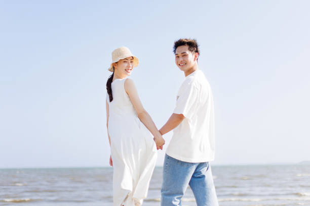 istock Young Asian couple holding hands at the beach 1677544355