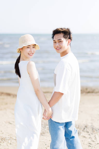 istock Young Asian couple holding hands at the beach 1677544356