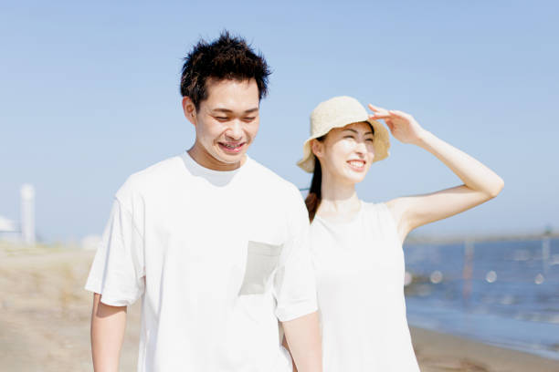 istock Young Asian couple walking by the beach 1677544368
