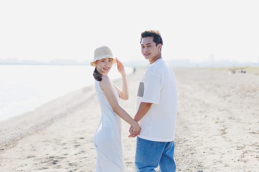 Young Asian couple walking by the beach with hands holding