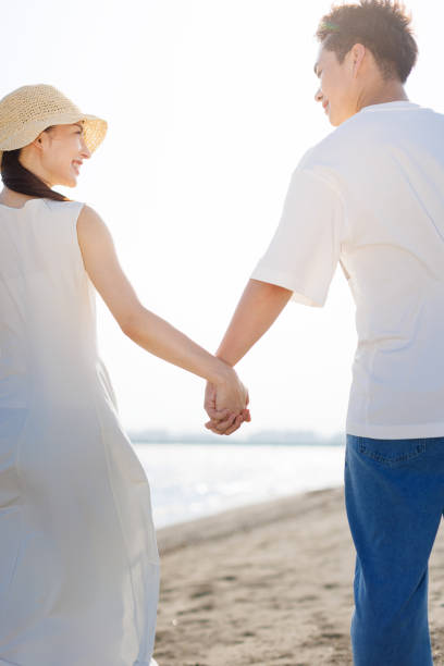 istock Young Asian couple walking by the beach with hands holding 1677544910