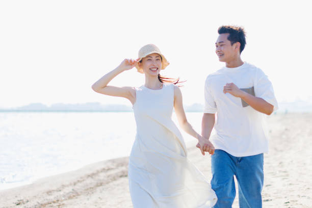 Young Asian couple walking by the beach with hands holding