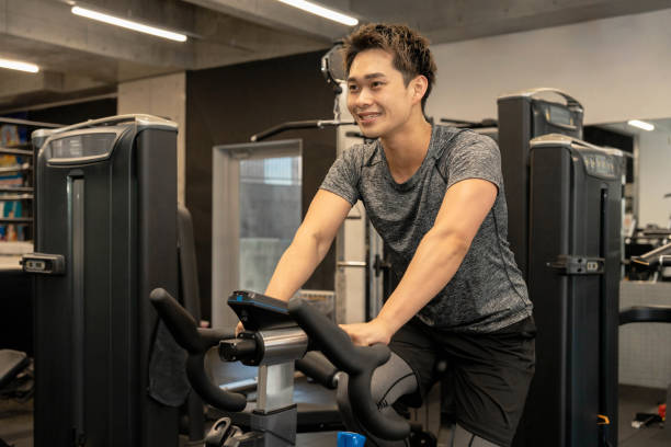 istock Young Asian man on exercise bike 1677547093