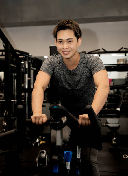 istock Young Asian man on exercise bike 1677547096