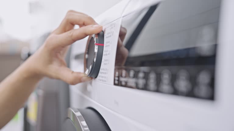 SLO MO: Close-up, side view of human hand adjusting the program on a clothes dryer machine and pushing start button to dry his washed clothes.