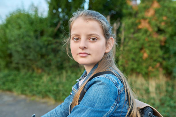 headshot portrait 10 years old girl with backpack outdoor, looking at camera - 10 11 years child human face female imagens e fotografias de stock