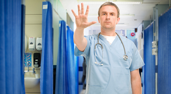 doc holds his hand up either saying no to violent patients , or stressing cleanliness