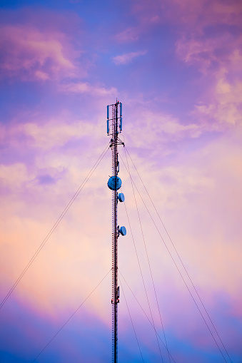 Cell tower with streamers at sunset.