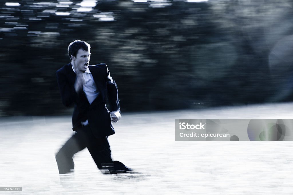 Banker on the run A gritty motion blurred image of a young banker running through a field screaming. Running Stock Photo