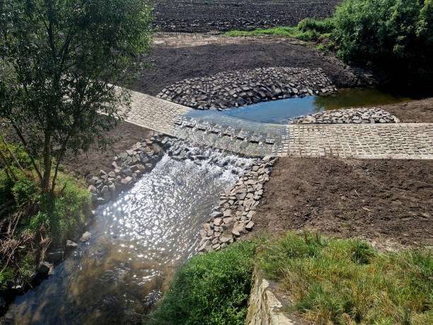 The dirt road leads across a stream that crosses river and continues when the flood road is impassable. restoration of watercourses and relocation upright drainage of fields into meandering The dirt road leads across a stream that crosses river and continues when the flood road is impassable. restoration of watercourses and relocation upright drainage of fields into meandering, reclamation,  bridge wade, wadebridge impassable limit stock pictures, royalty-free photos & images