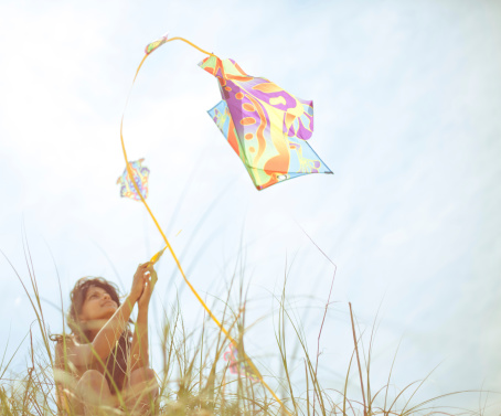 A beautiful Indian woman flying a kite from the top of a hill on a beautiful summery day at the beach in North carolina.