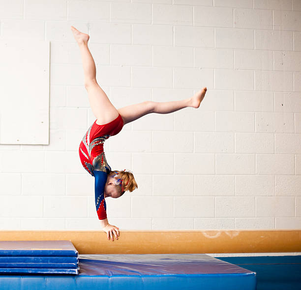 Young Gymnast Performing Walkover on Balance Beam stock photo