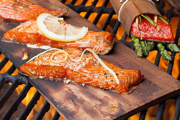 Three Grilled Salmon Filets on Cedar Plank Three wild-caught salmon filets on a cedar plank in a backyard grill.  Fist is bright reddish orange and is topped with lemon, dill and cracked pepper file_thumbview_approve.php?size=1&id=19631280 sockeye salmon filet stock pictures, royalty-free photos & images