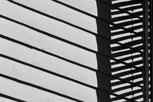 Detail of the shuttered window of a black and white wooden house. Monochrome building background