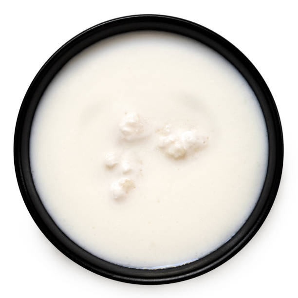 istock Milk with kefir grains in a black ceramic bowl isolated on white from above. 1677643291