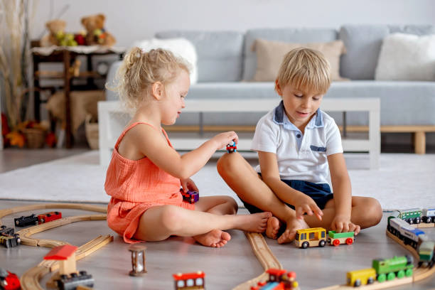 istock Two sweet children, siblings, playing with trains at home 1677644424