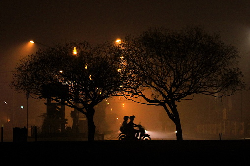 Palangka Raya City, Central Kalimantan Province, Indonesia - Septemner 29, 2015 - Motorcyclists pass through the streets of Palangka Raya City which are shrouded in thick smog at night. This condition occurs due to forest fires in the dry season.