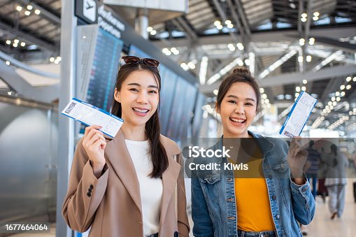 istock Portrait of Asian women standing in airport terminal at boarding gate. Attractive beautiful female tourist passenger feel happy and excited to go travel abroad by airplane for holiday vacation trip. 1677664064