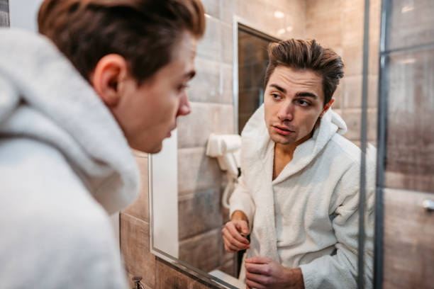 istock Young Man Looking At Himself In The Bathroom Mirror 1677677769