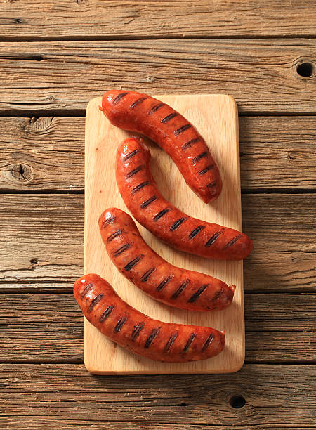 Four grilled sausages on wooden table